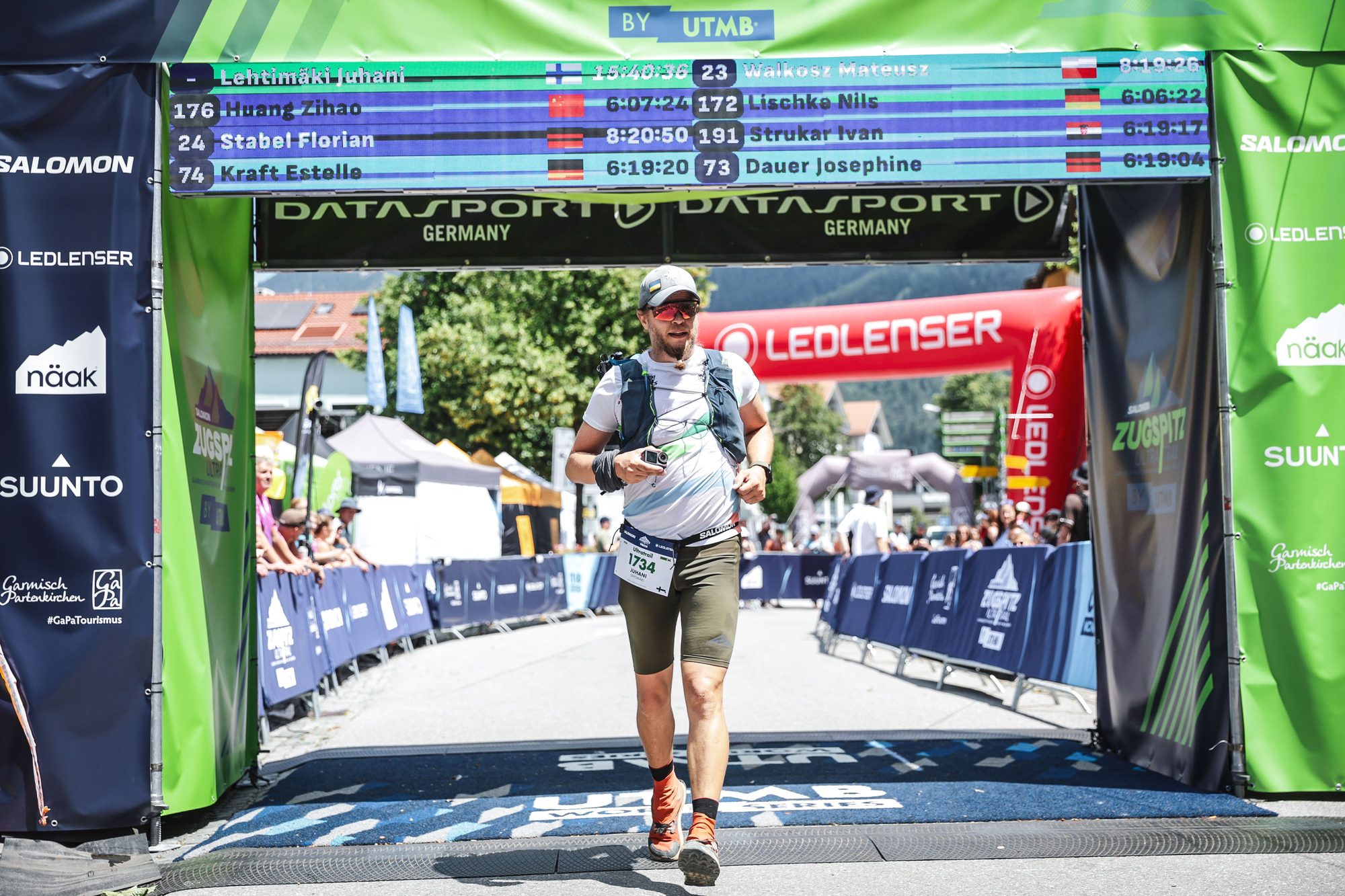 Juhani crossing a race finish line, arms raised