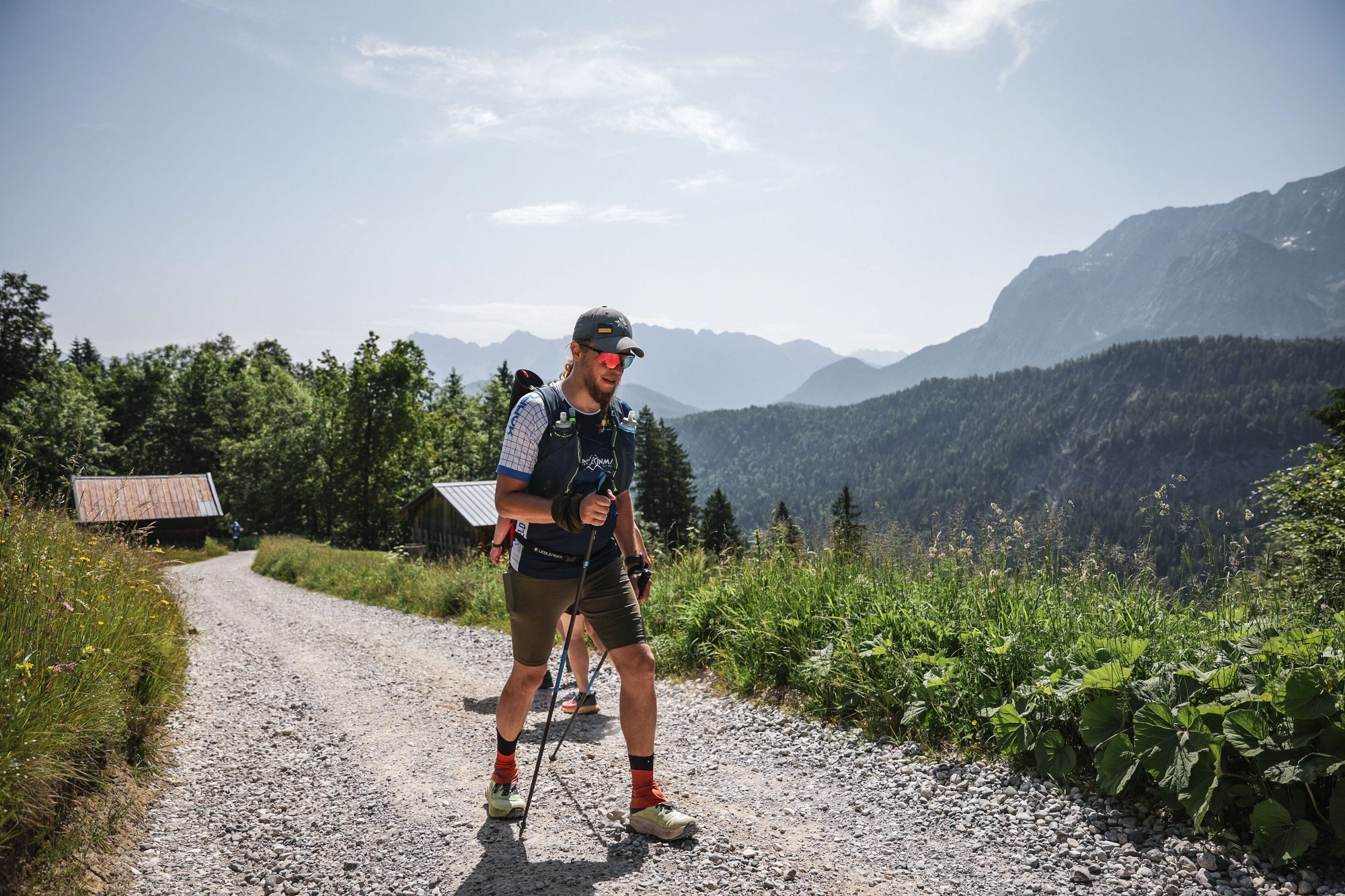 Juhani running a gravel trail below a high alpine peak
