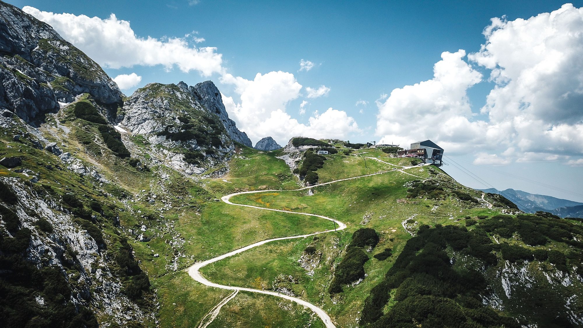 A winding singletrack trail along a green alpine ridge
